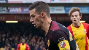 Nick Viergever in het zwart-gouden uittenue van FC Utrecht, met aanvoerdersband om zijn arm, schermt de bal af voor een speler van Go Ahead Eagles.